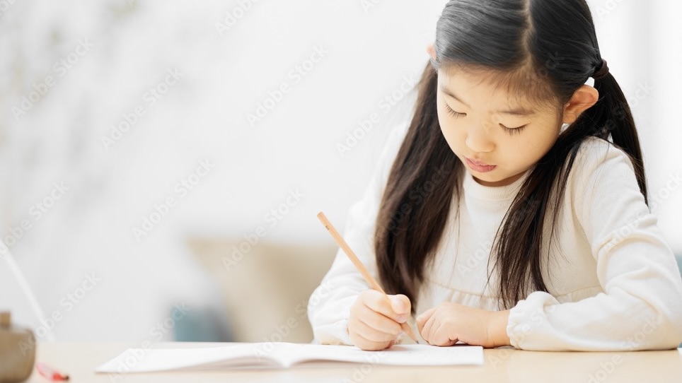 一人の女の子が鉛筆を手に勉強している